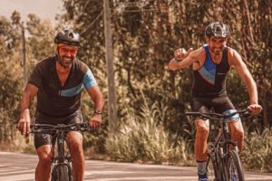 two men smiling while riding pedal bikes